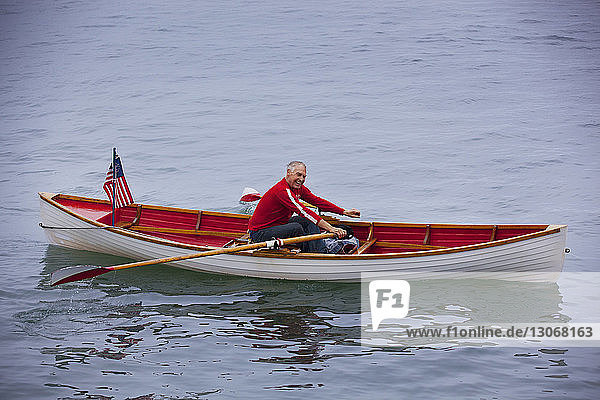 Happy senior man rowing boat in lake