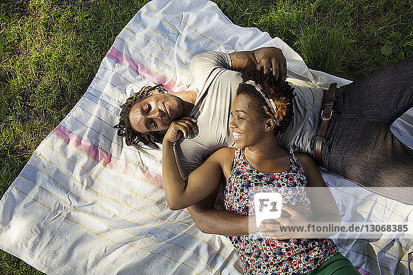 Hochwinkelansicht eines Paares  das sich auf dem Spielfeld im Park entspannt