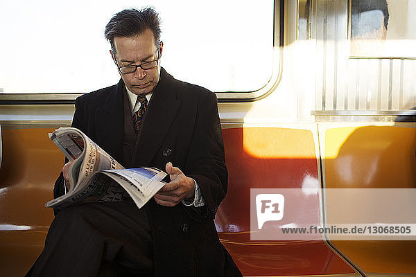 Geschäftsmann liest Zeitschrift während der Zugfahrt