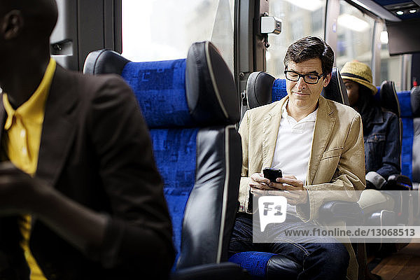 Mann benutzt Smartphone  während er im Bus sitzt