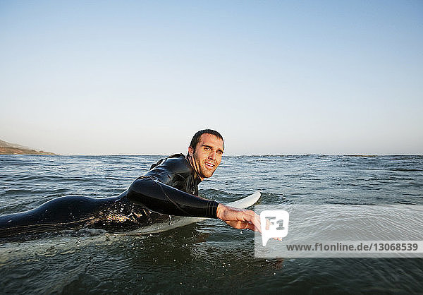 Porträt eines Mannes beim Surfen im Meer vor klarem Himmel