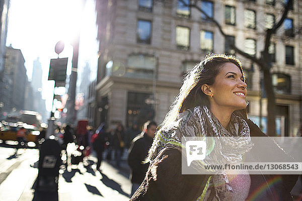 Lächelnde Frau schaut auf  während sie auf einem Fußweg in der Stadt geht