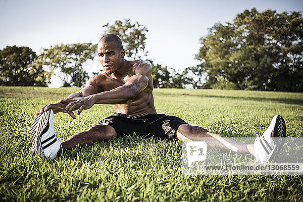 Sporty man exercising on grassy field at park