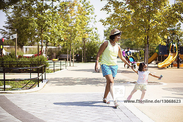 Mutter hält Tochter beim Spaziergang auf dem Spielplatz an der Hand