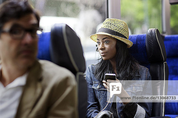 Frau schaut weg  während sie ein Mobiltelefon im Bus benutzt