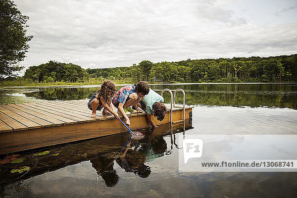 Kinder am Dock beim Angeln im See gegen den Himmel
