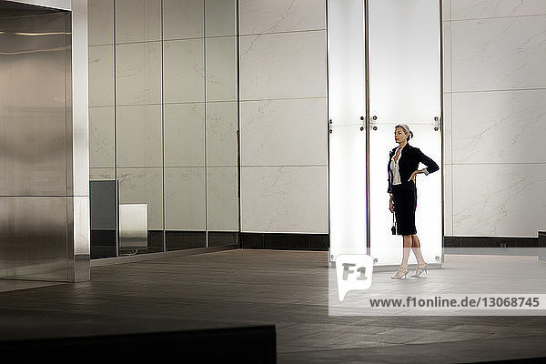 Confident businesswoman standing by illuminated blank column in city