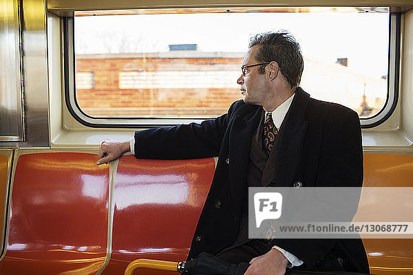 Geschäftsmann schaut weg  während er im Zug sitzt