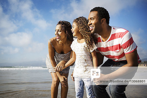 Glückliche Familie schaut weg  während sie am Strand am Ufer steht