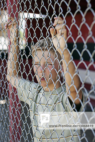 Portrait of boy leaning on chainlink fence