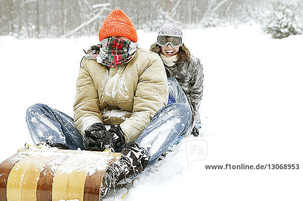 Vater und Tochter rodeln auf schneebedecktem Feld