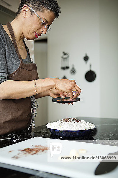 Frau streicht Schokoladenraspeln auf Sahnetorte