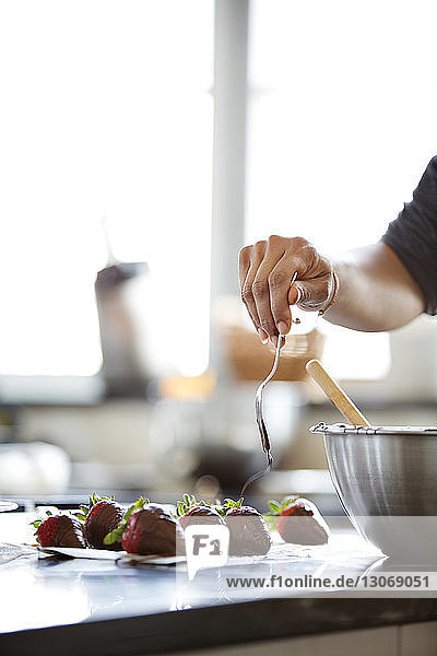 Frau streicht Schokolade auf Erdbeeren