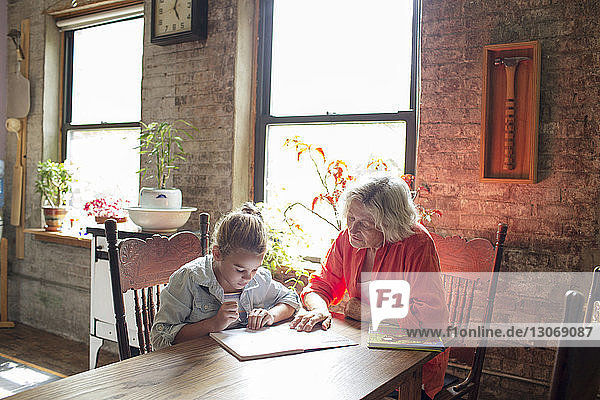 Frau hilft Enkelin bei den Hausaufgaben