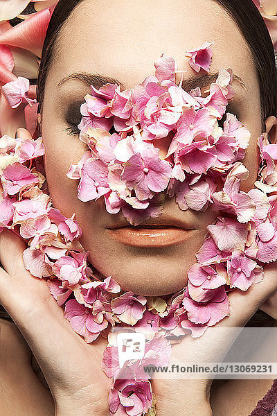 Close-up of woman face covered with flower petals