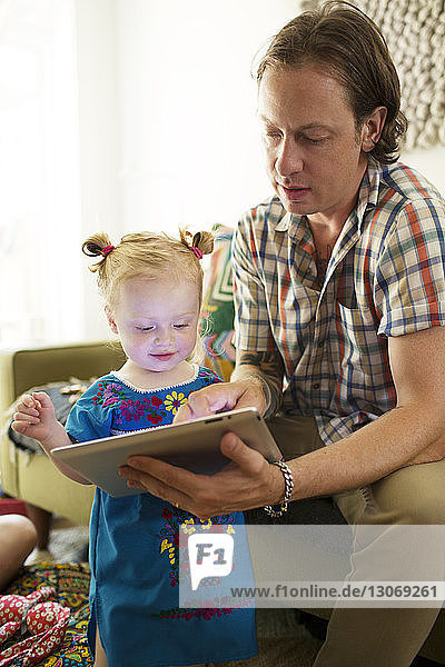 Vater zeigt der Tochter zu Hause einen Tablet-Computer