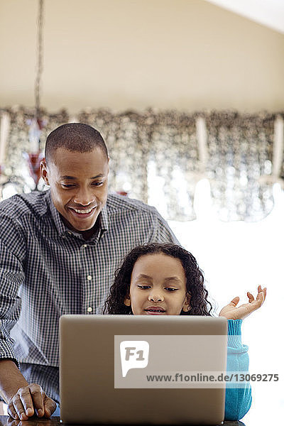 Niedrigwinkelansicht von Vater und Tochter mit Laptop-Computer