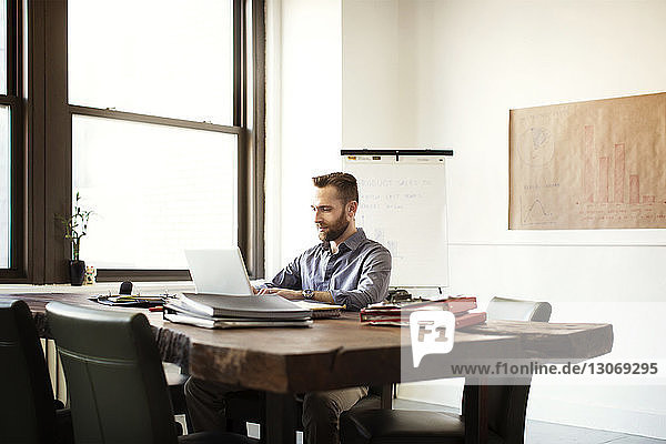 Businessman working on laptop computer while sitting at desk in office