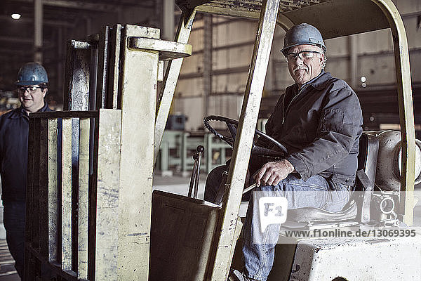 Portrait of man sitting on forklift in factory