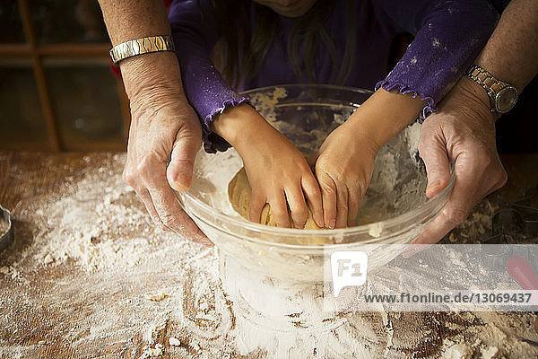 Ausgeschnittenes Bild eines Mädchens mit Großmutter  die Teig knetet  während sie Kekse backt