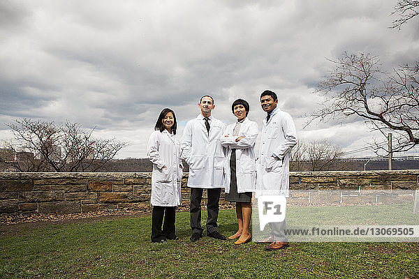 Portrait of doctors standing on field against cloudy sky