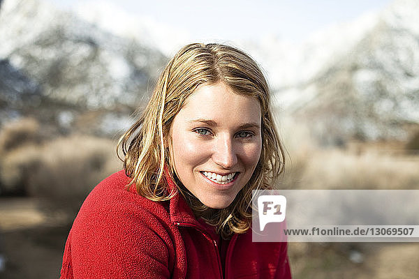 Porträt einer lächelnden Frau mit rotem Pullover in den Bergen