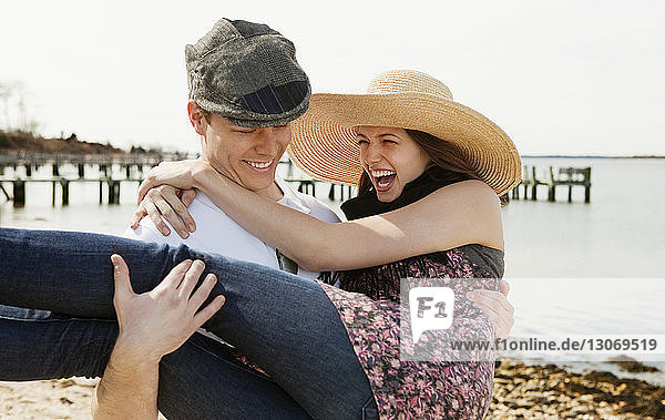 Man lifting woman while walking at beach