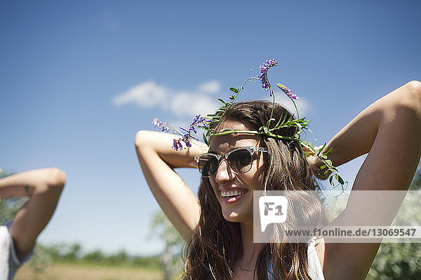 Happy woman wearing tiara while standing against blue sky