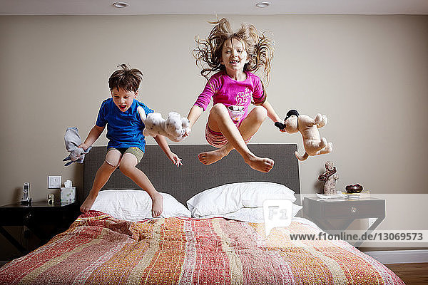 Verspielte Kinder  die zu Hause auf dem Bett hüpfen