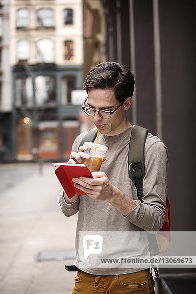 Man drinking juice while using tablet computer