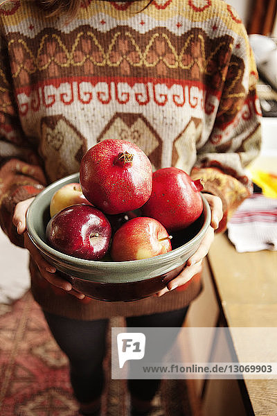 Ausgeschnittenes Bild einer Frau  die Früchte hält  während sie zu Hause steht