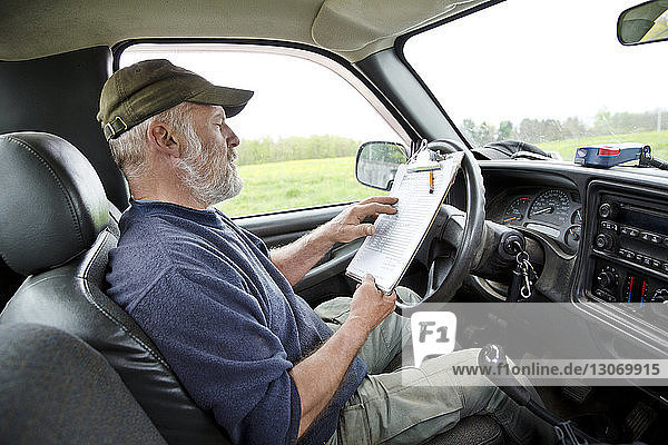 Mann liest  während er im Auto sitzt