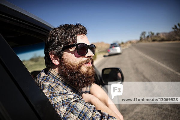 Man leaning out of window while sitting in car