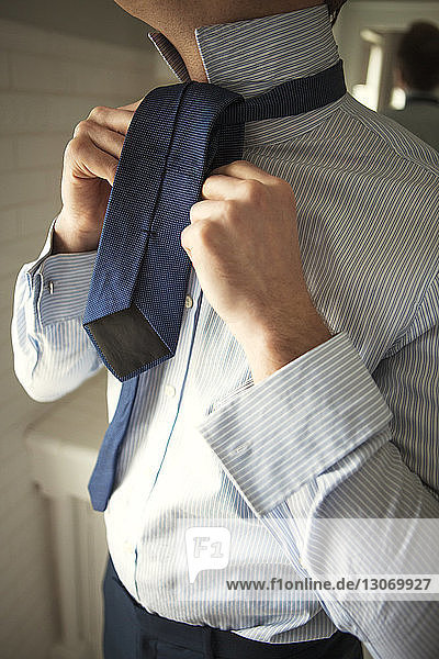 Mann bindet Krawatte ein  während er zu Hause steht
