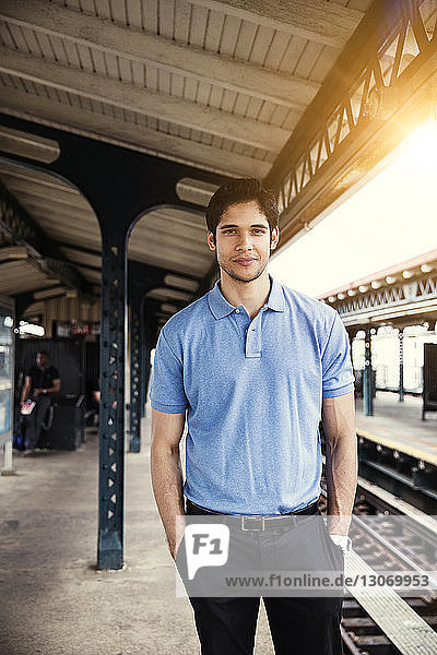 Portrait of man with hands in pockets standing at railroad platform