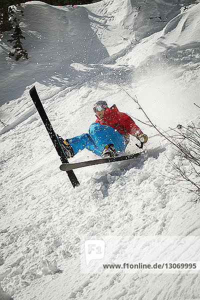 Skifahrer fällt auf schneebedecktes Feld