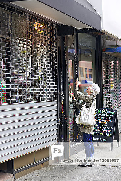 Ältere Frau öffnet Ladenladen