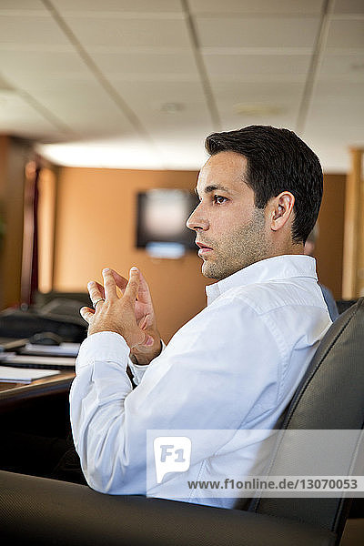Geschäftsmann schaut weg  während er während einer Sitzung im Büro sitzt