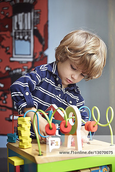 Junge spielt im Kindergarten mit hölzernem Labyrinthspielzeug