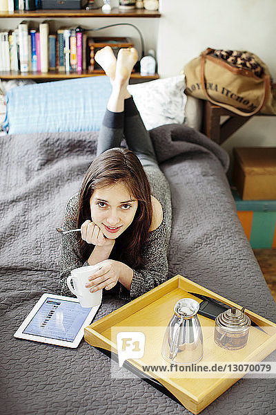 Portrait of woman with tablet computer lying on bed