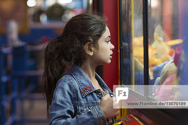 Girl playing toy grabbing game in amusement arcade