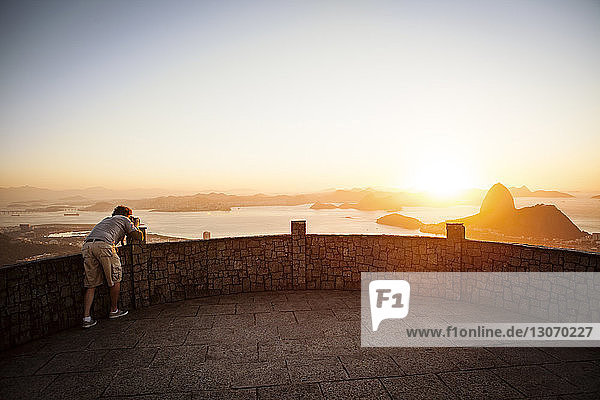 Man photographing Sugarloaf Mountain while standing at observation point during sunset