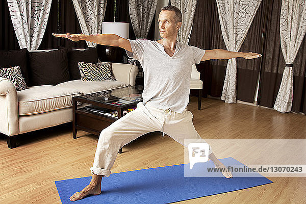 Man practicing warrior 2 yoga positing at home