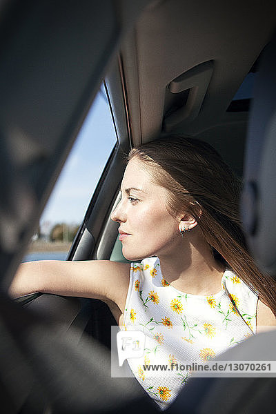Woman looking through car window while traveling