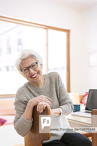 Portrait of happy senior woman sitting on chair at home