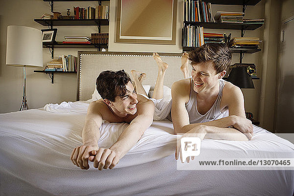 Happy gay couple relaxing on bed at home