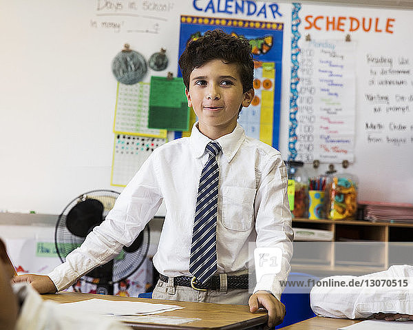 Boy standing at desk in classroom
