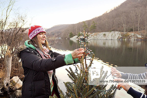 Freunde schmücken Weihnachtsbaum am Seeufer