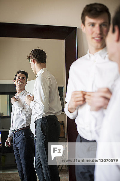 Gay couple looking at each other while getting dressed at home