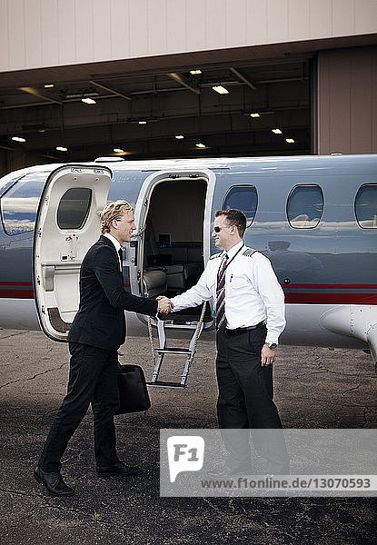 Geschäftsmann schüttelt dem Piloten die Hand  während er am Flugzeug steht
